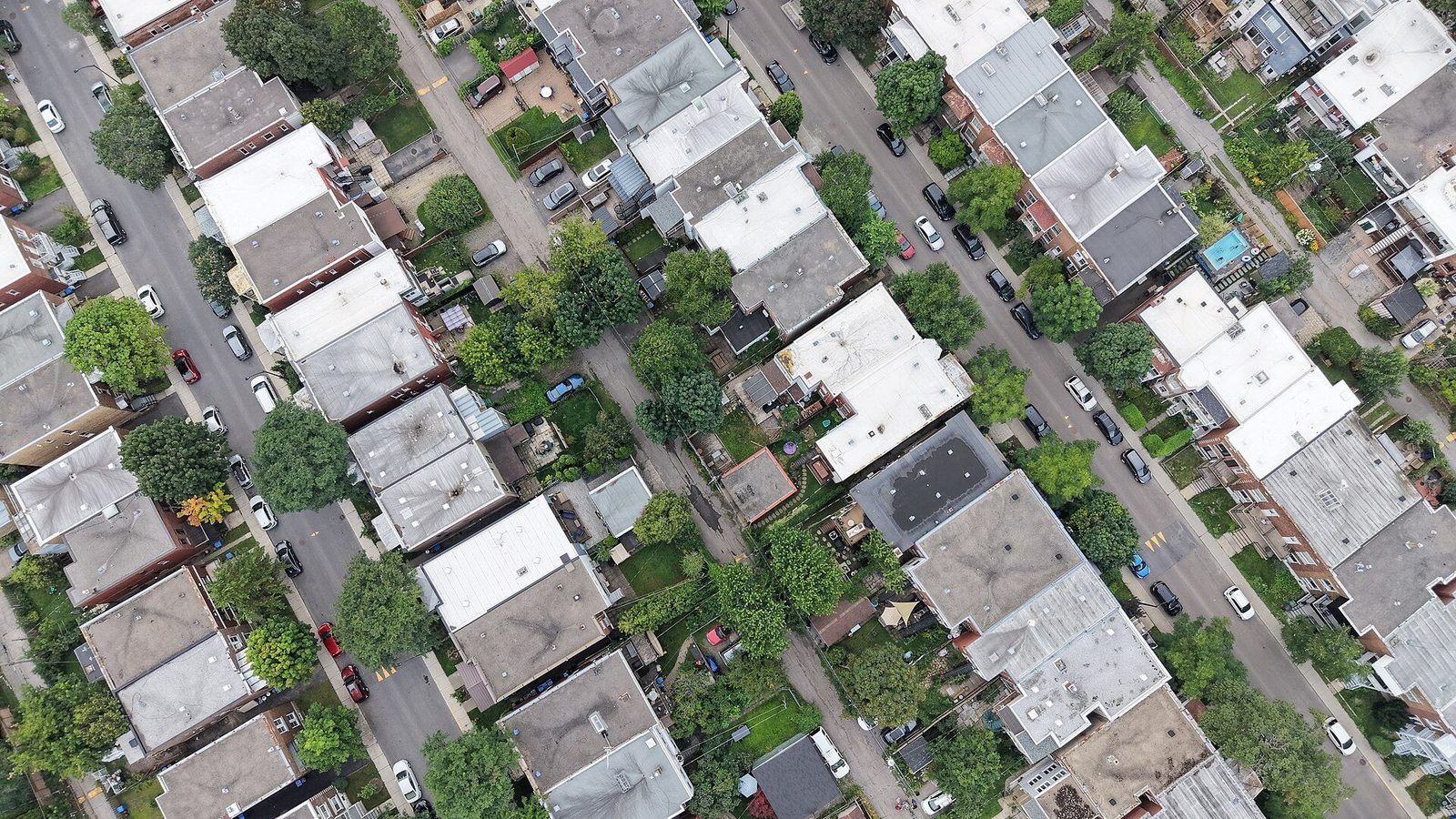 Aerial view of rows of two- and three-storey plex buildings with flat roofs, back gardens and trees along parallel streets in Verdun, Montreal